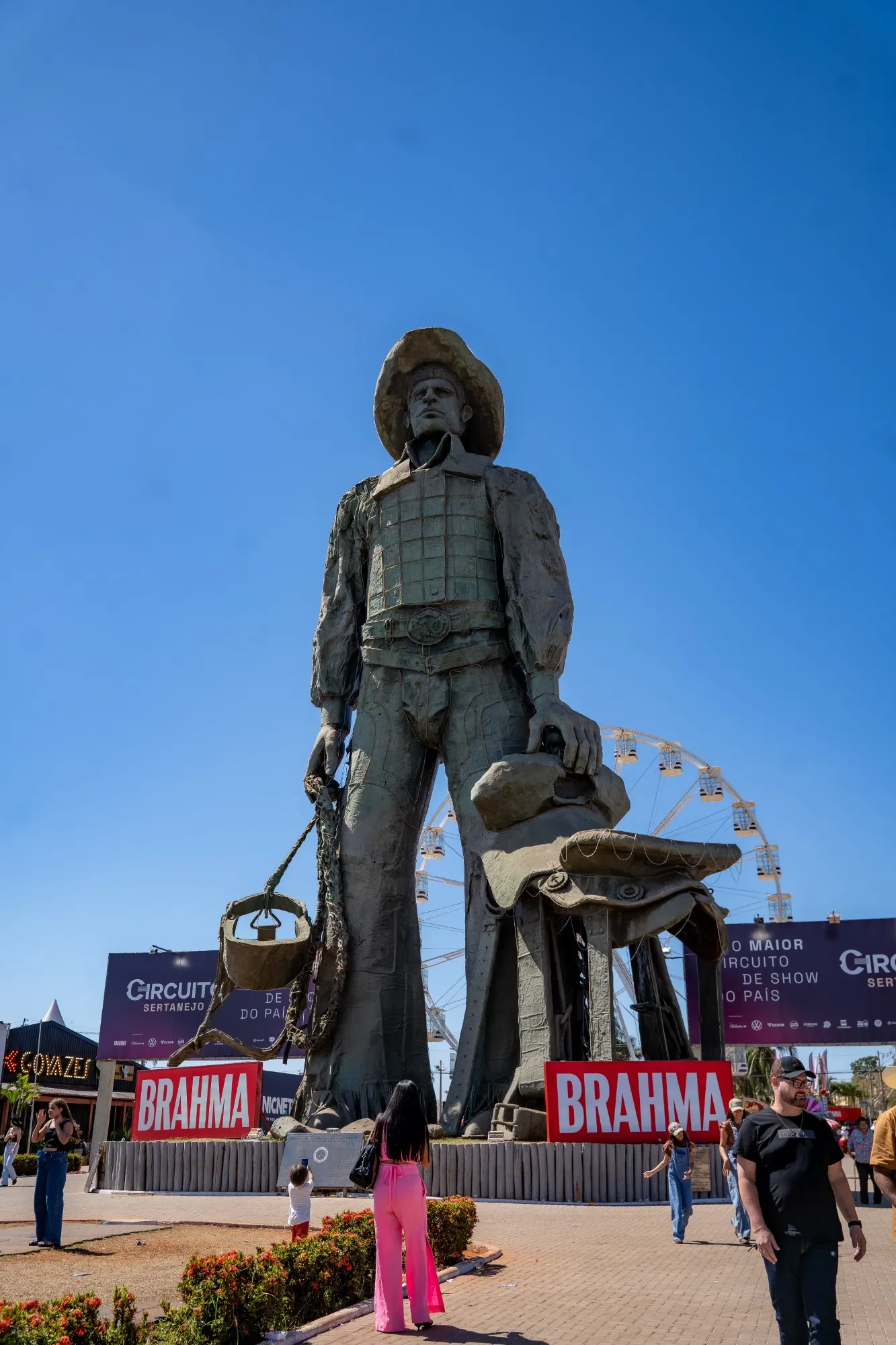 Estátua do peão no parque do Circuito Sertanejo em Barretos, com a roda-gigante ao fundo